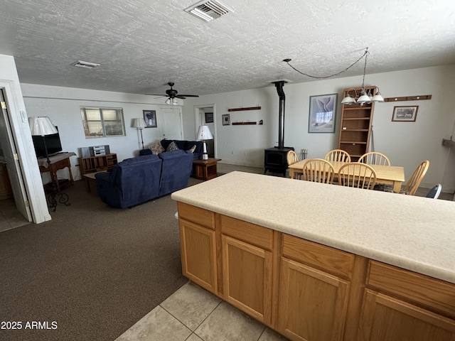 kitchen with decorative light fixtures, a wood stove, light tile patterned floors, ceiling fan, and a textured ceiling