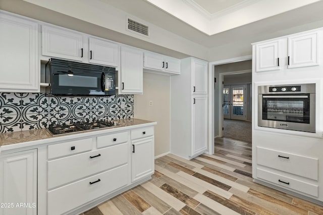 kitchen featuring stainless steel appliances, tasteful backsplash, light wood-type flooring, crown molding, and white cabinets