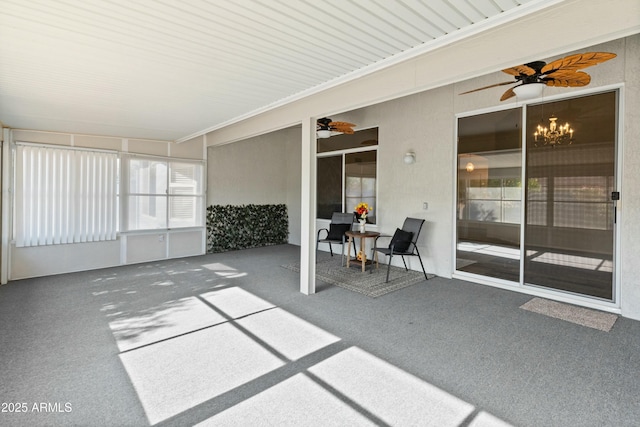 unfurnished sunroom with ceiling fan with notable chandelier