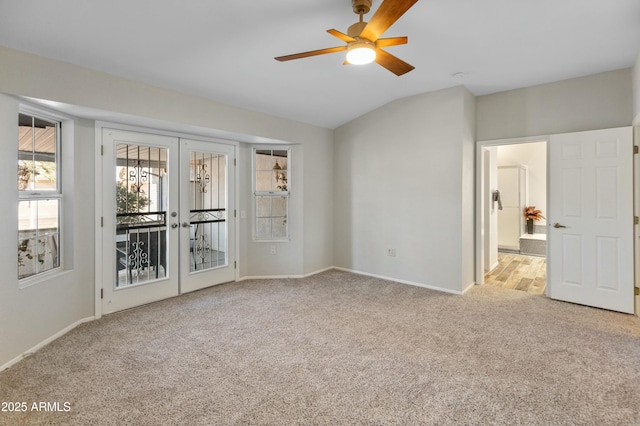 carpeted spare room with ceiling fan, lofted ceiling, and french doors