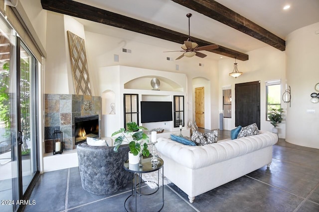 living room with a towering ceiling, built in features, a fireplace, beamed ceiling, and ceiling fan