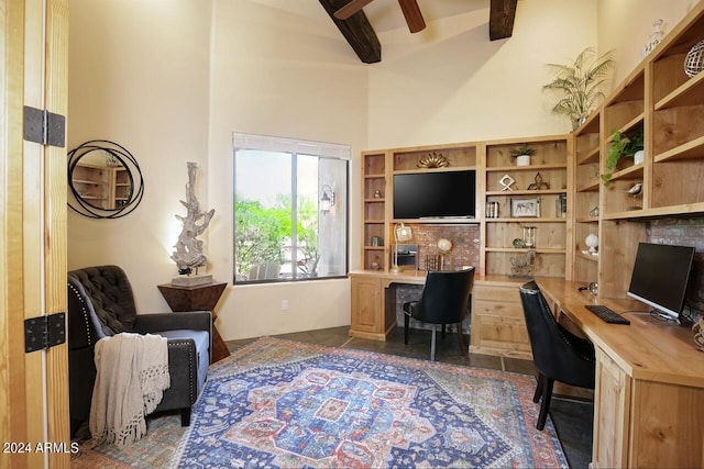 home office featuring ceiling fan, a towering ceiling, built in desk, and beamed ceiling