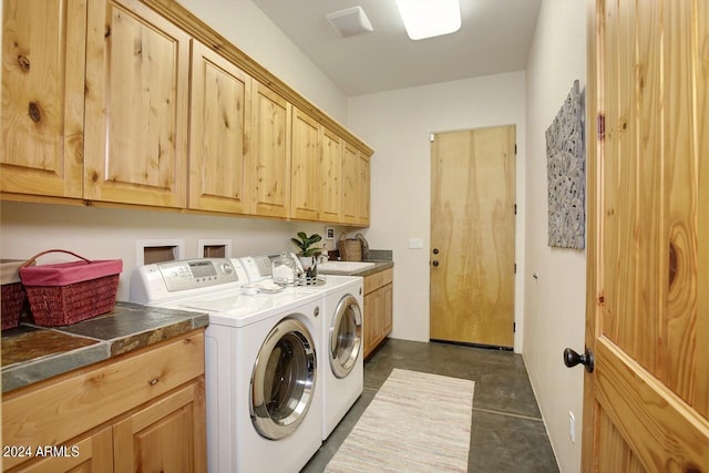 clothes washing area with cabinets and separate washer and dryer