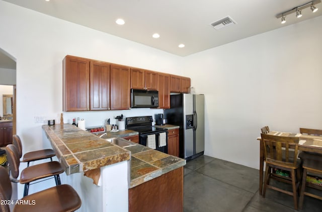 kitchen featuring sink, a breakfast bar, kitchen peninsula, and black appliances