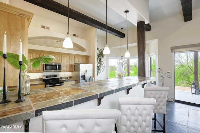 kitchen with appliances with stainless steel finishes, pendant lighting, beamed ceiling, a breakfast bar area, and plenty of natural light