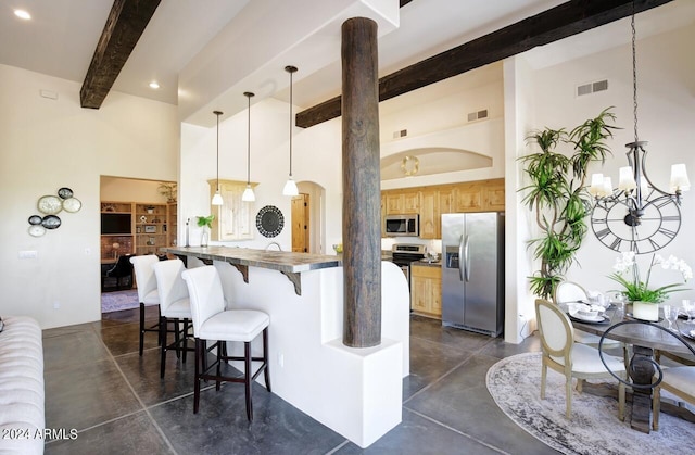 kitchen featuring pendant lighting, a breakfast bar area, a chandelier, stainless steel appliances, and beam ceiling