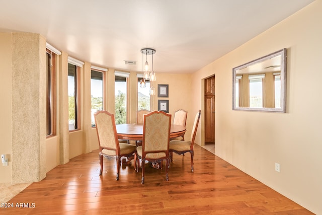 dining area with light wood-type flooring and an inviting chandelier