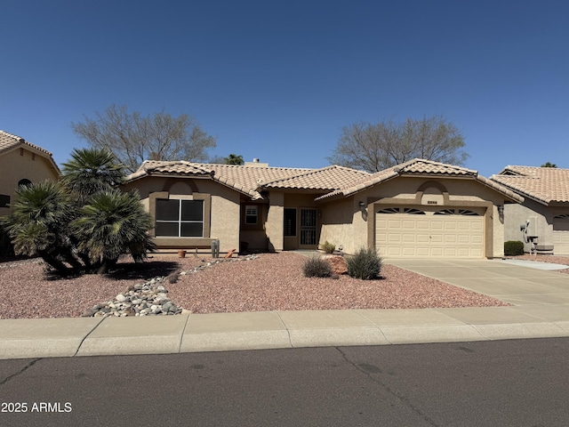 mediterranean / spanish home featuring stucco siding, a garage, concrete driveway, and a tiled roof