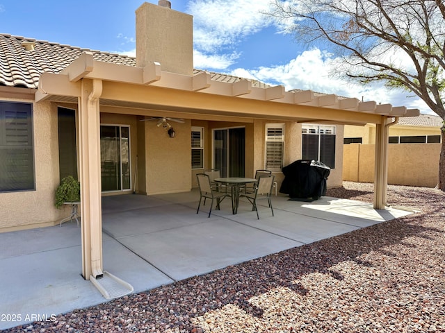 rear view of house with fence, a chimney, stucco siding, a tile roof, and a patio area