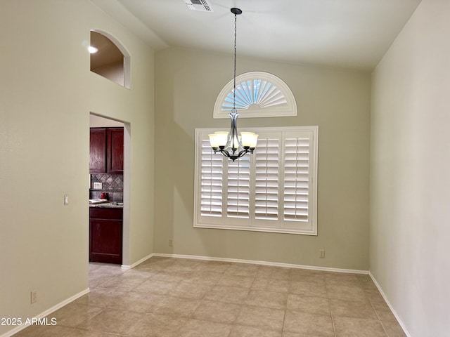 empty room with an inviting chandelier, visible vents, baseboards, and vaulted ceiling