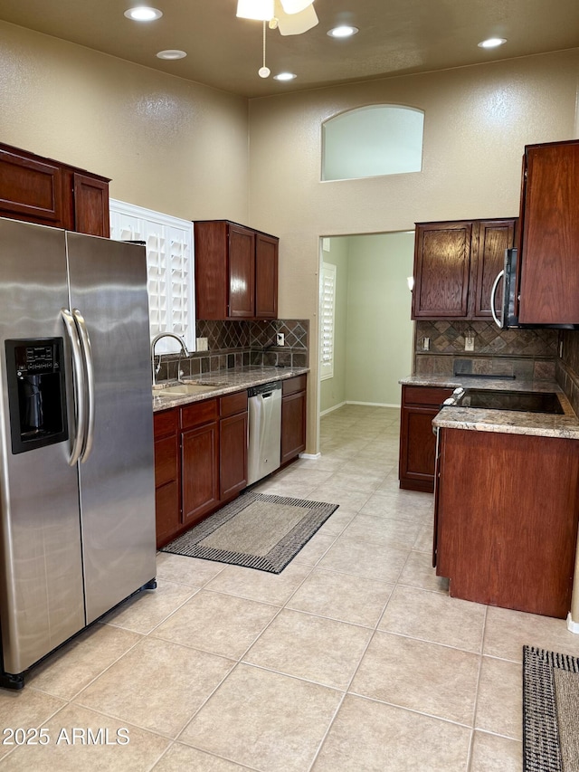 kitchen featuring light tile patterned flooring, backsplash, stainless steel appliances, and light stone countertops