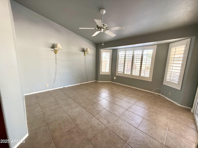 spare room featuring tile patterned floors, a ceiling fan, baseboards, and vaulted ceiling