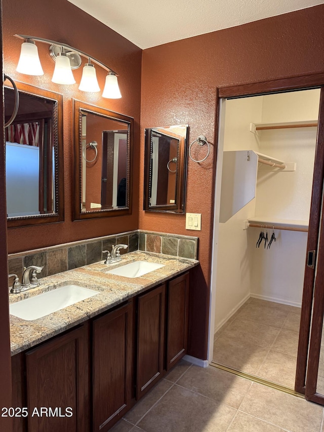 bathroom with double vanity, tile patterned floors, a spacious closet, and a sink