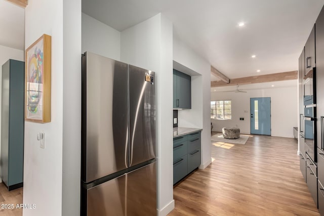 kitchen featuring ceiling fan, appliances with stainless steel finishes, beam ceiling, and light wood-type flooring