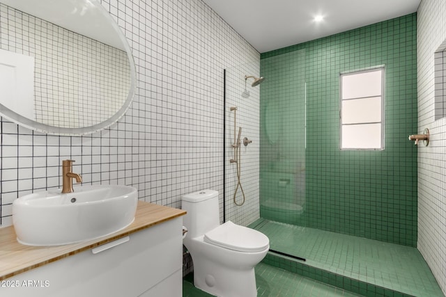 bathroom featuring vanity, toilet, tile walls, and a tile shower