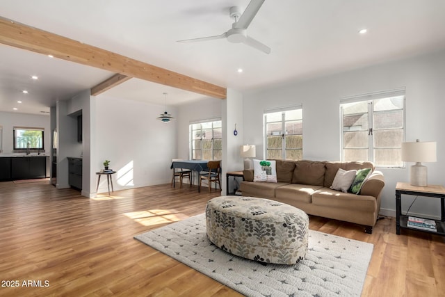 living room with beamed ceiling, ceiling fan, sink, and light hardwood / wood-style floors