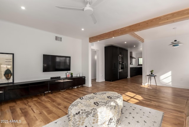 living room with hardwood / wood-style flooring, ceiling fan, and beam ceiling