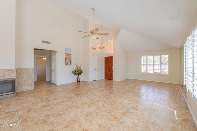 interior space with ceiling fan with notable chandelier, high vaulted ceiling, and a fireplace