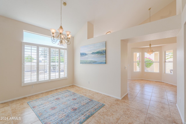 tiled empty room featuring a wealth of natural light, lofted ceiling, and a chandelier