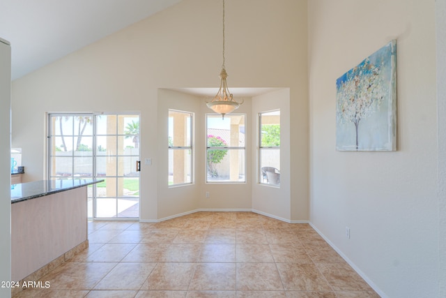 unfurnished dining area featuring a healthy amount of sunlight, high vaulted ceiling, and light tile floors