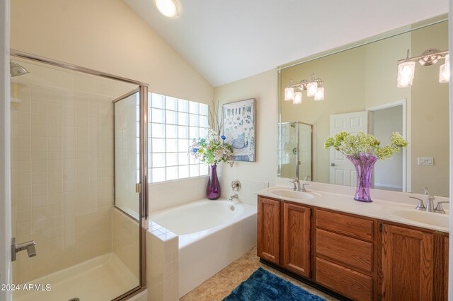 bathroom with tile flooring, independent shower and bath, vaulted ceiling, and double sink vanity