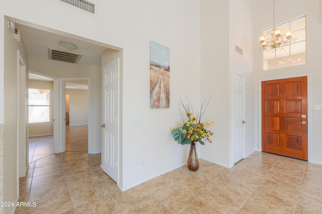 tiled entrance foyer with a towering ceiling and an inviting chandelier