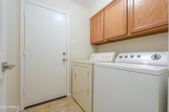 washroom featuring washing machine and dryer, light tile flooring, and cabinets