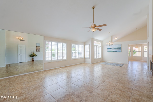 unfurnished living room with ceiling fan with notable chandelier, a wealth of natural light, high vaulted ceiling, and light tile floors