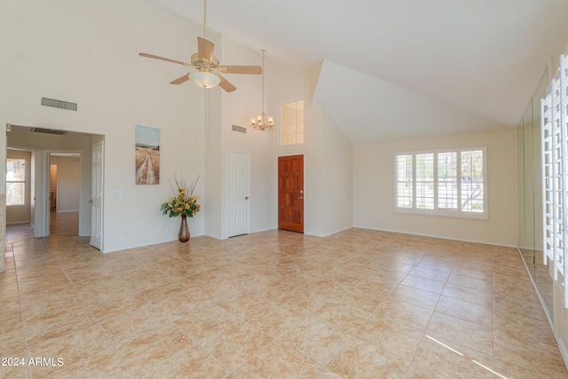 tiled spare room featuring high vaulted ceiling and ceiling fan with notable chandelier