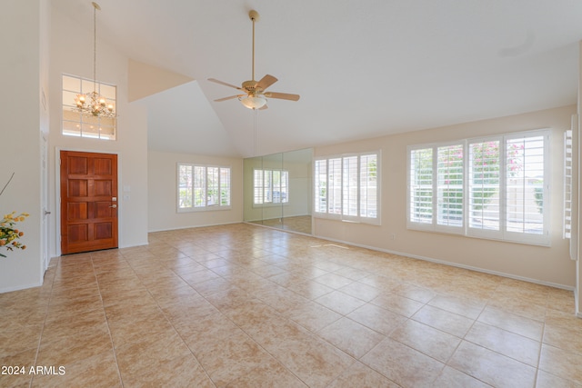 interior space featuring ceiling fan with notable chandelier, plenty of natural light, high vaulted ceiling, and light tile flooring