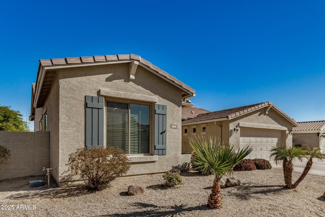 view of side of property featuring an attached garage, a tile roof, and stucco siding