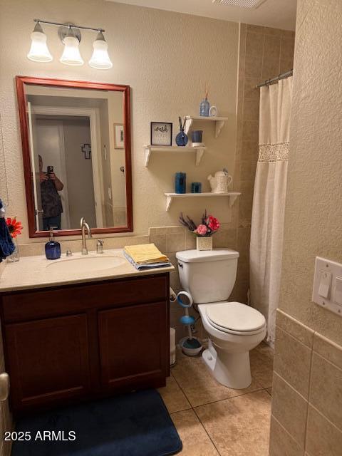 bathroom with a textured wall, vanity, toilet, tile patterned floors, and a shower with shower curtain