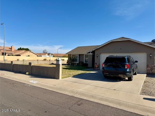ranch-style house featuring an attached garage, stucco siding, fence, and driveway