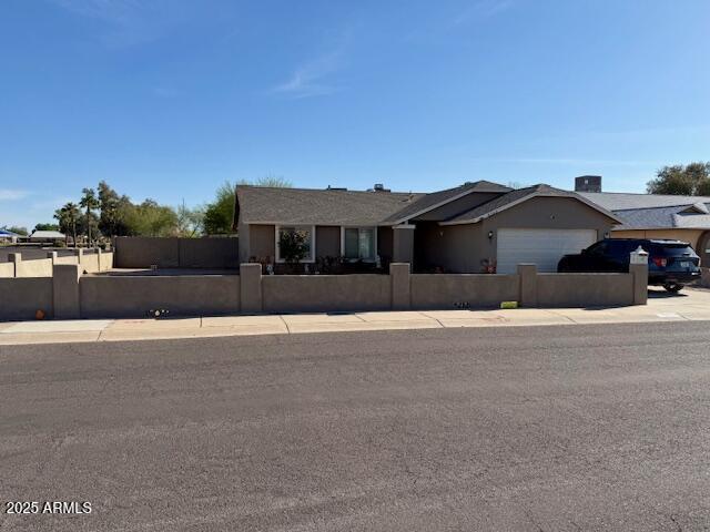 ranch-style home with an attached garage, a fenced front yard, and driveway