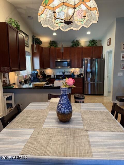 kitchen with a kitchen bar, dark countertops, a peninsula, stainless steel appliances, and recessed lighting