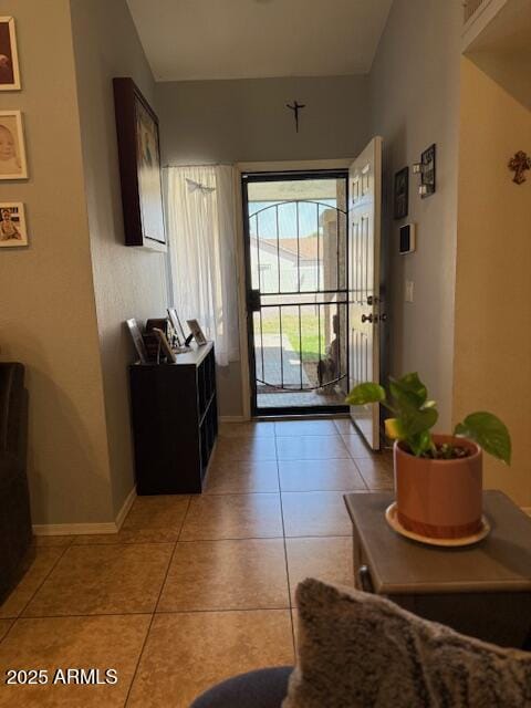 doorway featuring baseboards and light tile patterned flooring