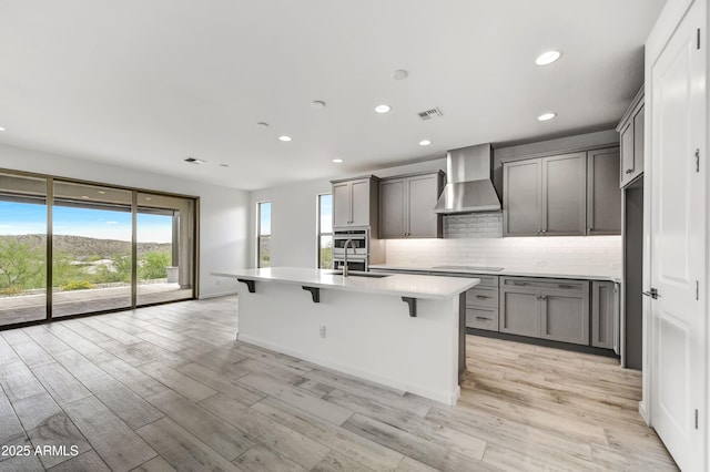 4128 Desert Moon Dr, Wickenburg, AZ 85390 - kitchen with wall chimney exhaust hood, stainless steel oven, gray cabinetry, recessed lighting, and backsplash