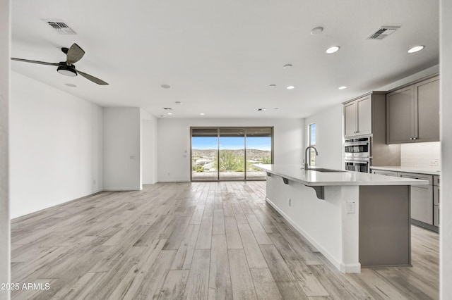 4128 Desert Moon Dr, Wickenburg, AZ 85390 - kitchen featuring open floor plan, stainless steel double oven, a sink, light wood-style floors, and recessed lighting