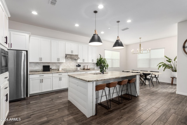 kitchen with dark wood-type flooring, a center island with sink, white cabinets, pendant lighting, and appliances with stainless steel finishes