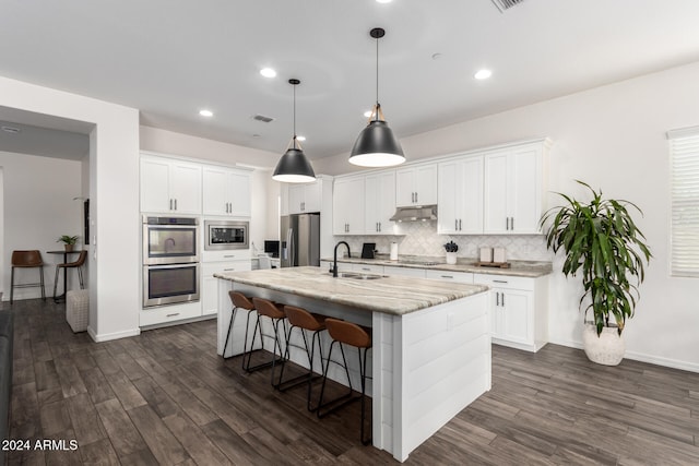 kitchen with stainless steel appliances, white cabinetry, a center island with sink, and sink