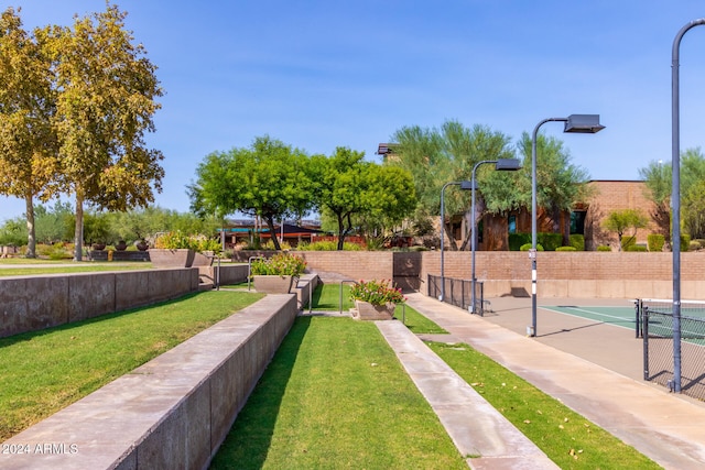 view of property's community featuring tennis court and a yard