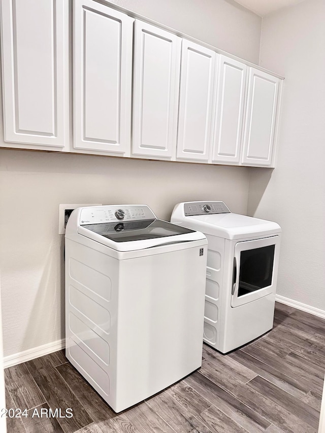 washroom featuring wood-type flooring, cabinets, and washer and dryer