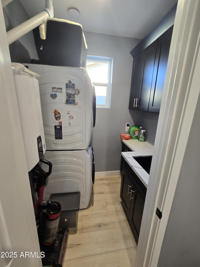 kitchen with stacked washer / drying machine, sink, and light hardwood / wood-style floors