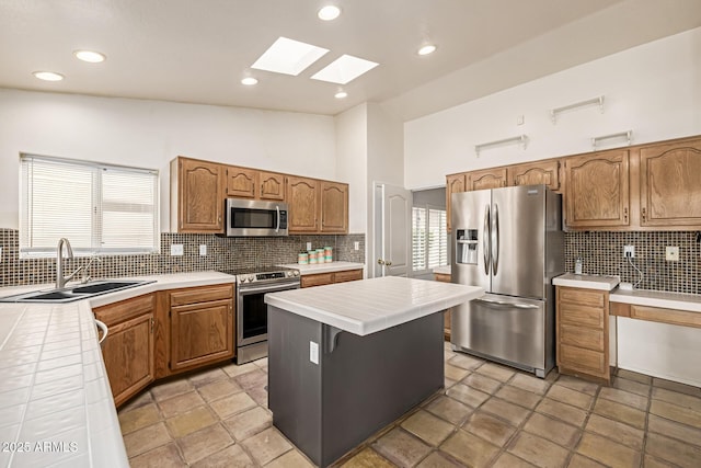 1146 W Sea Fog Dr, Gilbert, AZ 85233 - kitchen featuring stainless steel appliances, a sink, tile countertops, a skylight, and backsplash