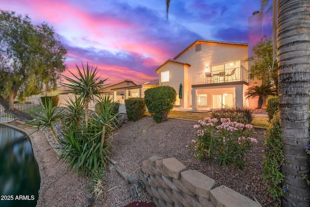 1146 W Sea Fog Dr, Gilbert, AZ 85233 - back of property at dusk featuring a balcony, stucco siding, and fence