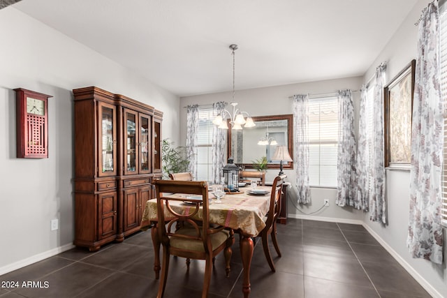 dining area featuring plenty of natural light, dark tile patterned floors, and a notable chandelier