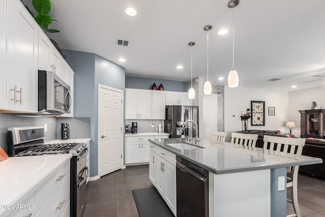 kitchen with an island with sink, white cabinets, a breakfast bar, and appliances with stainless steel finishes