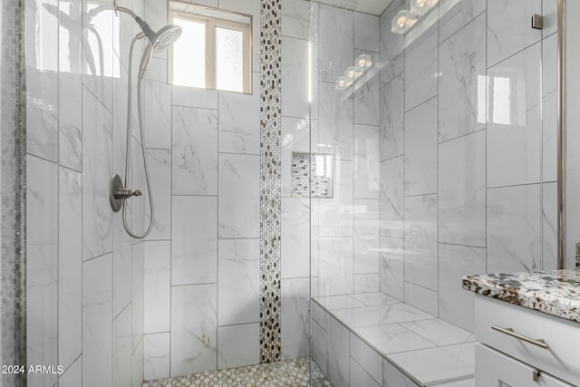 bathroom with a tile shower and vanity