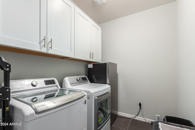 washroom featuring cabinets, dark tile patterned flooring, and washer and dryer