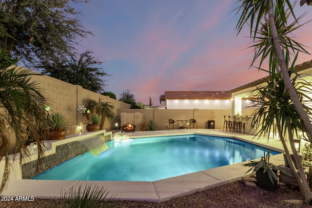 pool at dusk featuring a patio area